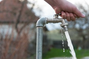 Wasser läuft aus geöffnetem Wasserhahn heraus.