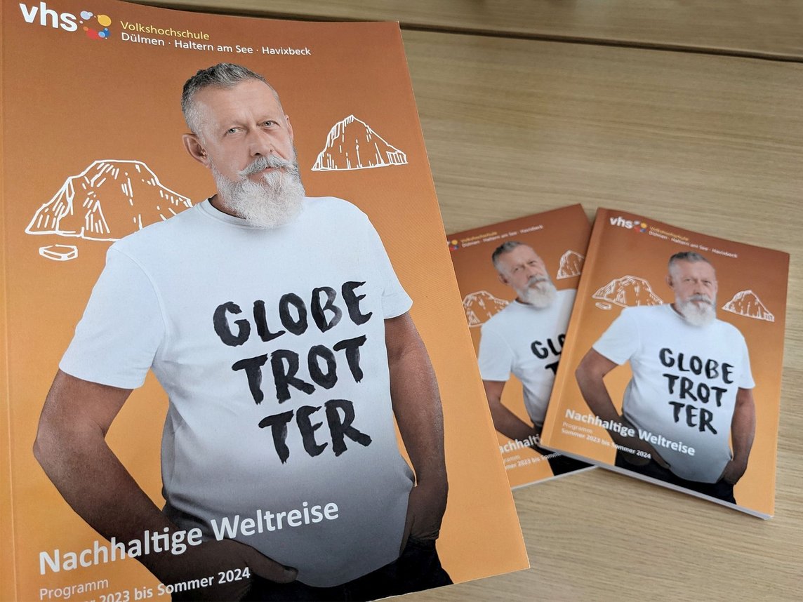 Das Bild zeigt das Cover des neuen VHS-Programmheftes. Darauf ist ein bärtiger Mann zu sehen, auf dessen T-Shirt die Aufschrift "Globetrotter" zu lesen ist.