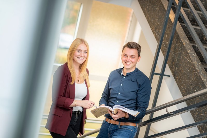 Ausbildung & Studium Zwei Mitarbeitende stehen im Treppenhaus und besprechen Unterlagen.