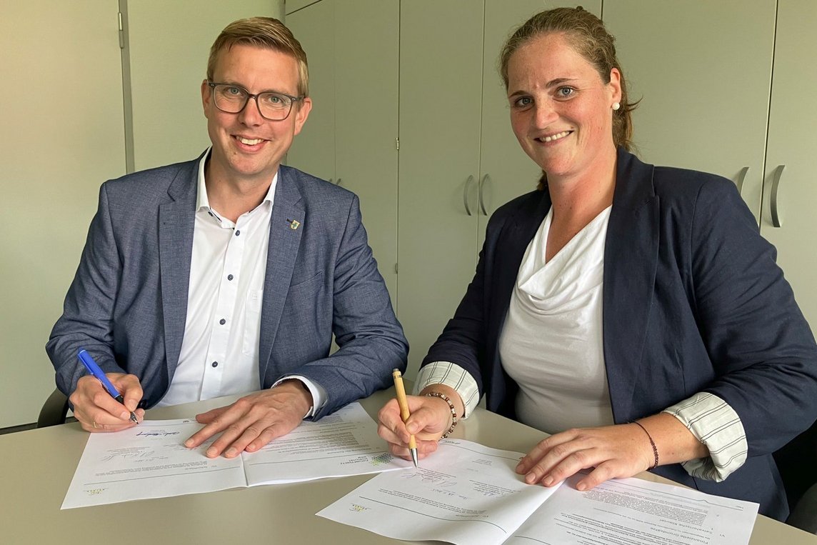 Dieses Foto zeigt Bürgermeister Carsten Hövekamp und Franca Börsch vom Zukunftsnetz Mobilität NRW bei der Unterzeichnung der Rahmenvereinbarung. 