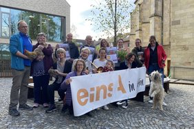 Das Bild zeigt eine Gruppe von Menschen und Tieren auf dem Kirchplatz.