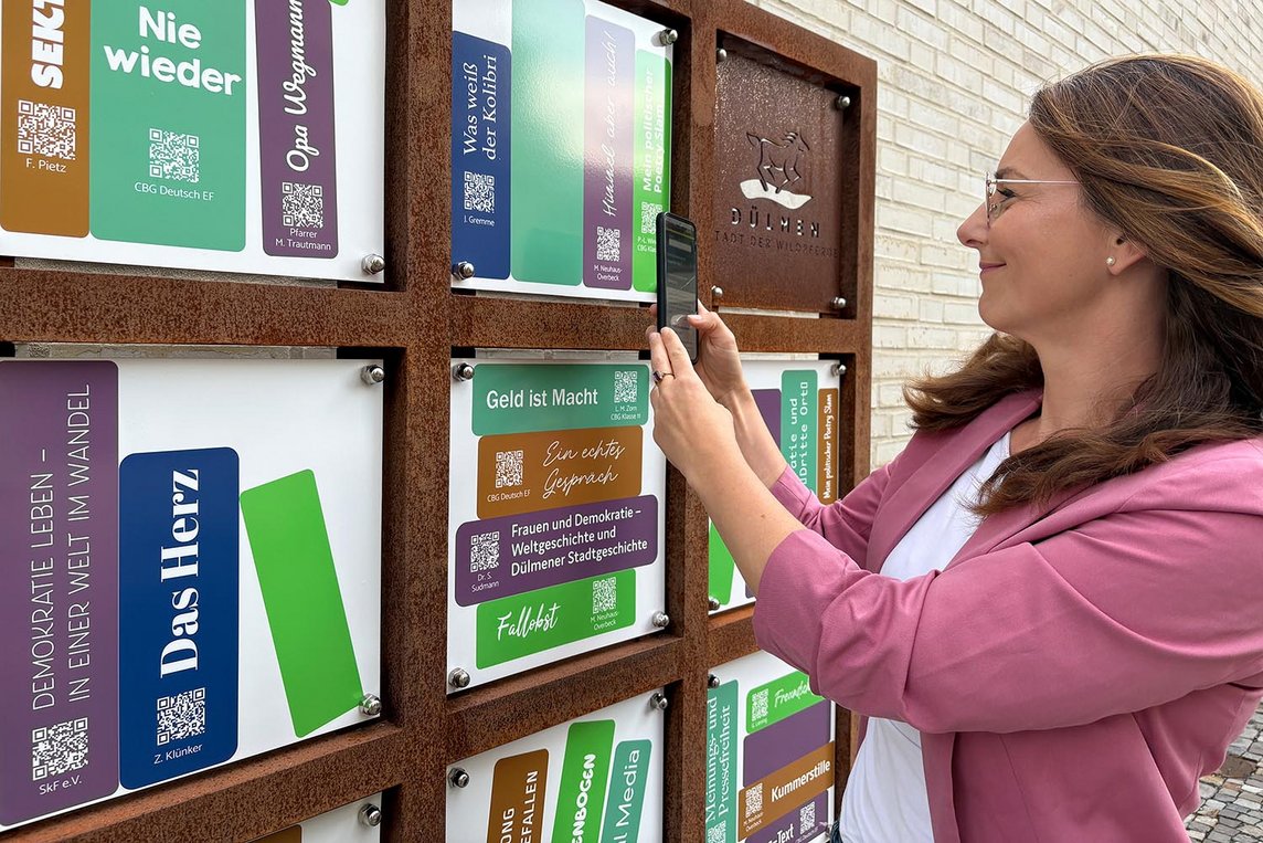 Dieses Foto zeigt Sabrina Rustige vor dem digitalen Bücherregal.