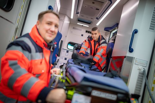 Zwei Mitarbeitende des Rettungsdienstes ziehen eine Trage aus dem Rettungswagen.