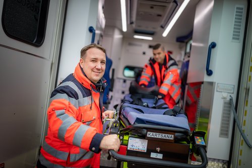 Mitarbeitende des Rettungsdienstes ziehen eine Trage aus einem Rettungswagen.