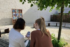 Das „Digitale Bücherregal“ und die heimeligen Sitzgelegenheiten auf dem Kirchplatz laden zum Schmökern in entspannter Atmosphäre ein. Per QR-Code werden die Texte auf dem Smartphone oder Tablet abgerufen. Fotos: Stadt Dülmen/Kannacher
