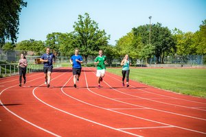 Das Bild zeigt Läuferinnen und Läufer auf einem Sportplatz.