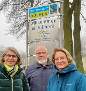 Freuen sich über die neuen Schilder, die an den Ortseingängen – hier: Lüdinghauser Straße – auf die Zertifizierung als „Fairtrade-Stadt“ hinweisen: Elvira Lipp (li.) und Helmut Tissen vom Vorstand des EineWeltLadens sowie VHS-Leiterin Dr. Marie Hologa. Foto: Stadt Dülmen/Kannacher