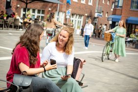 Dieses Foto zeigt zwei Bürgerinnen mit Smartphone in der Innenstadt