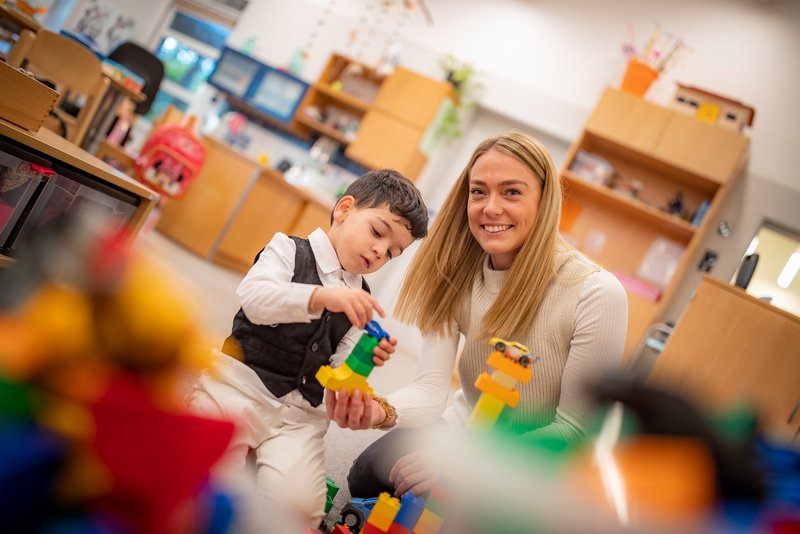 Kind und Erzieherin spielen mit Bauklötzen.