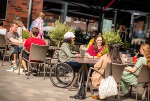 Das Bild zeigt Menschen an einem Tisch vor einem Restaurant,