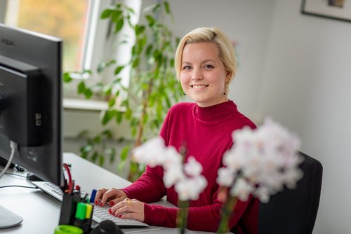 Mitarbeiterin sitzt am Schreibtisch vor einem Computer.