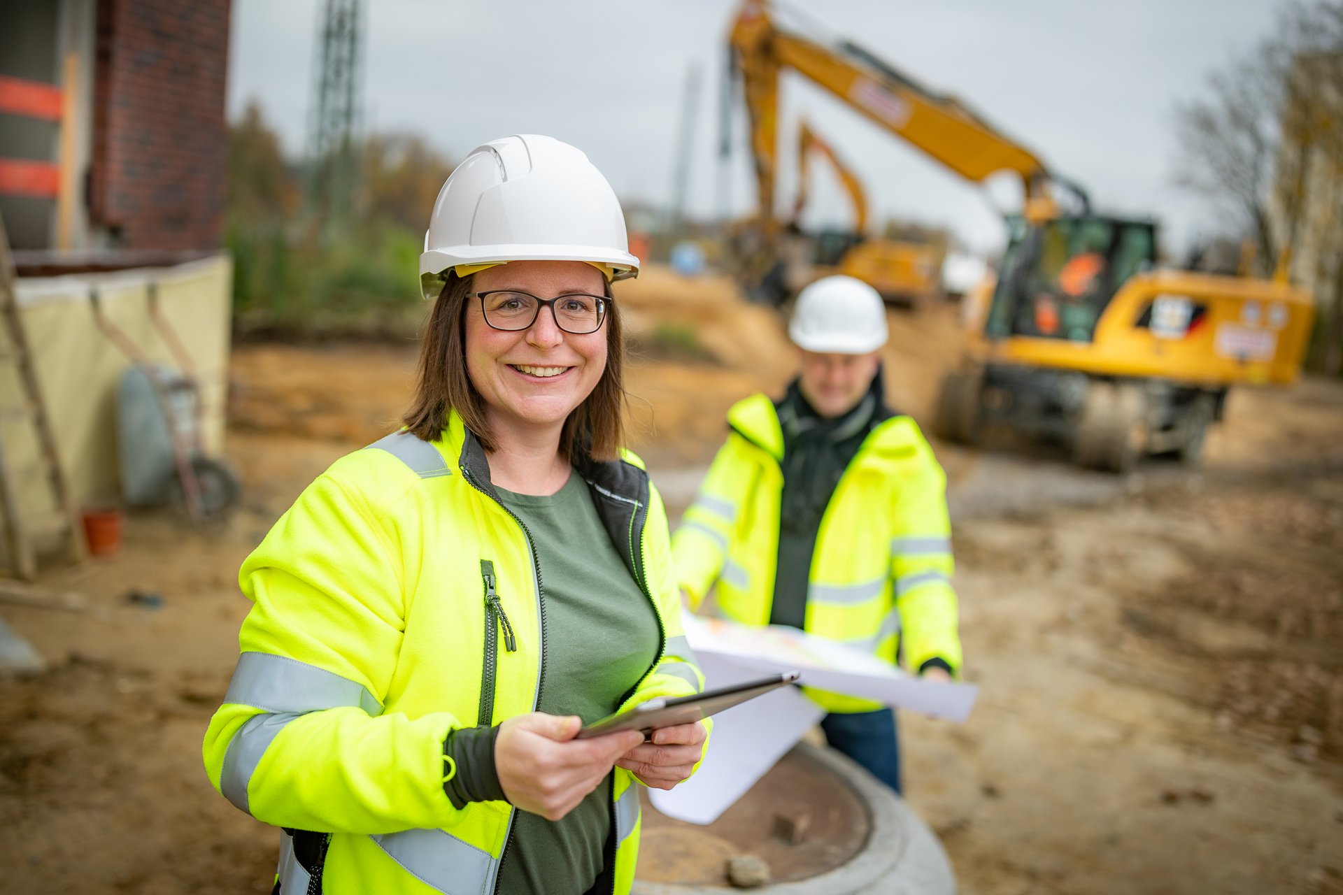 Mitarbeitende besprechen Pläne auf einer Baustelle.